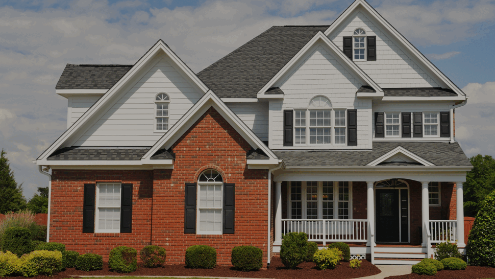 Two-story brick and white siding house with gray shingle roof and front porch
