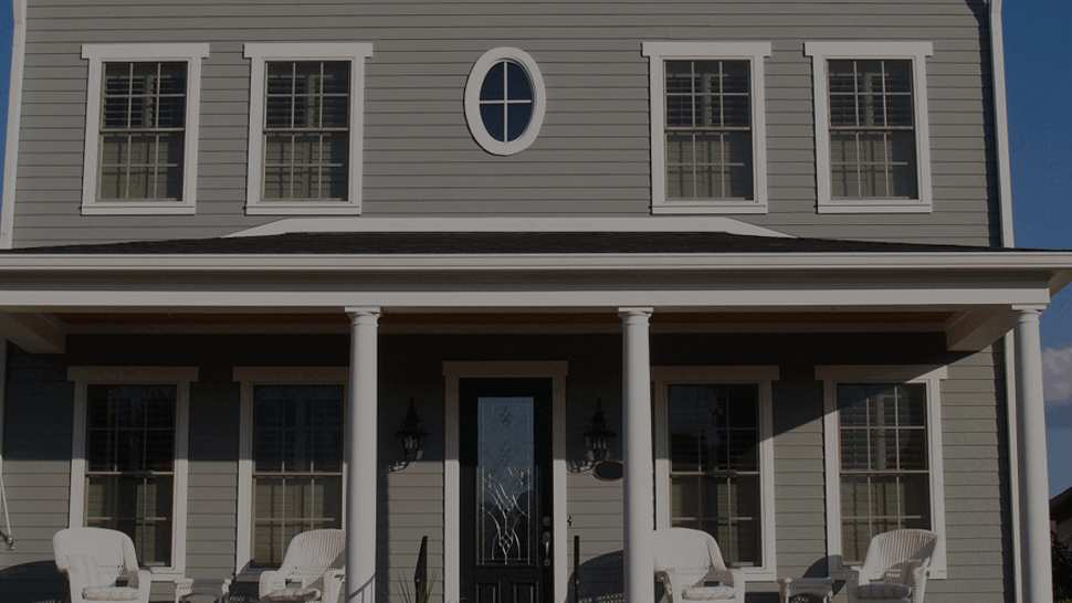 Symmetrical front facade with multiple windows, oval accent window, and central door