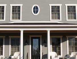 Gray two-story house with white columns, black front door, and porch seating