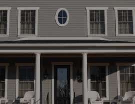 Symmetrical front facade with multiple windows, oval accent window, and central door