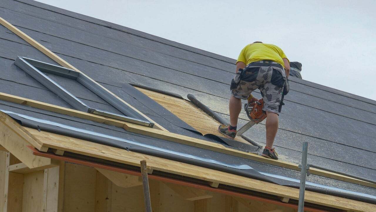 man cutting an opening in a roof for skylight