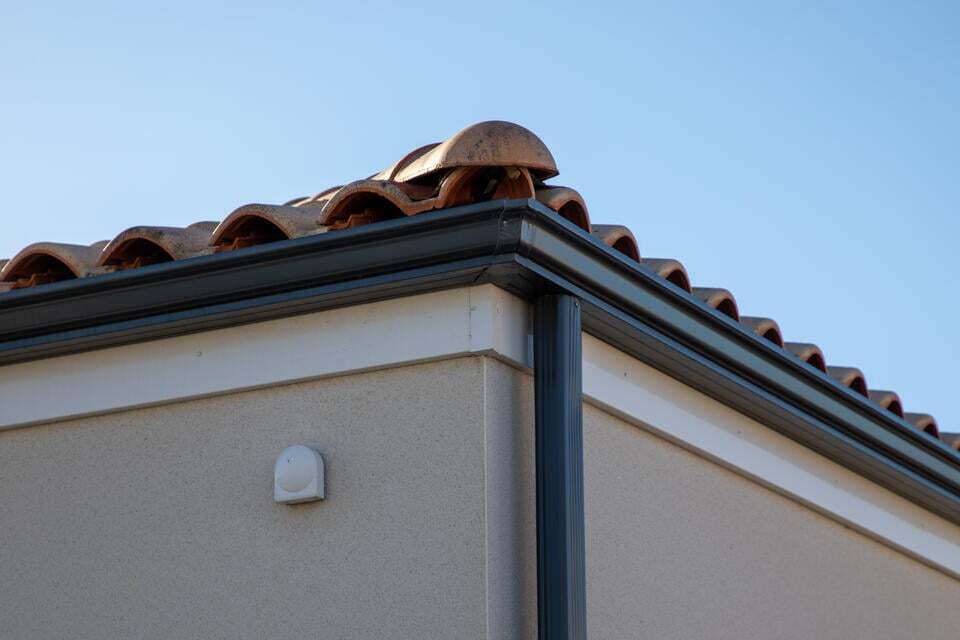 aluminum gutters-black metal gutter system on stucco sided house