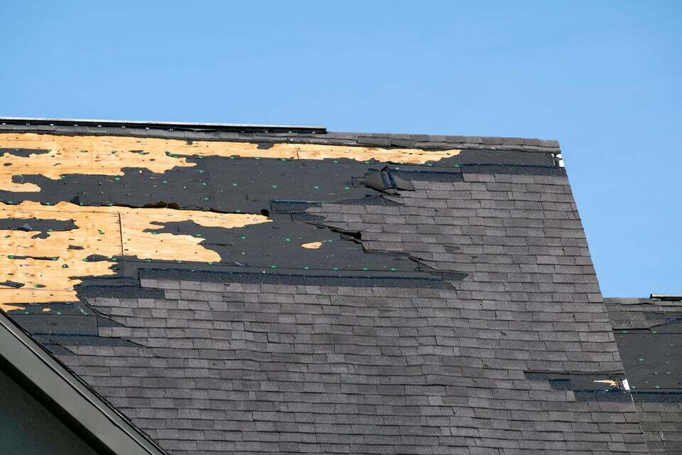 roof repair vs replacement-gray shinlge roofing with massive sections missing due to damage