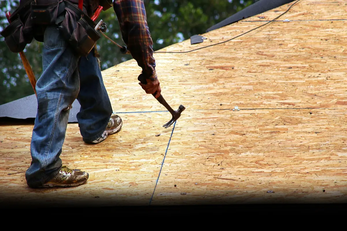 roofer with a hammer performing a roof tear off