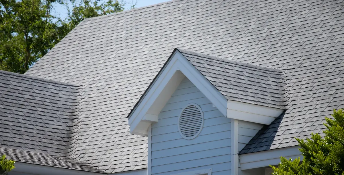 house roof with asphalt shingle roof and tree in the back