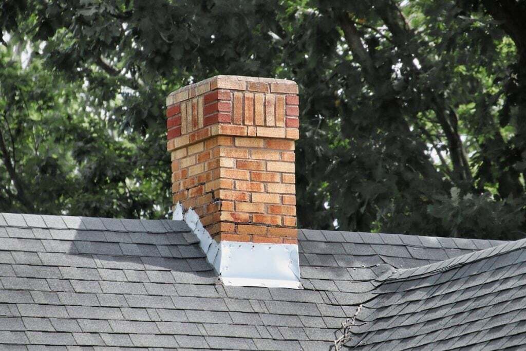 An old chimney on a shingles rooftop.