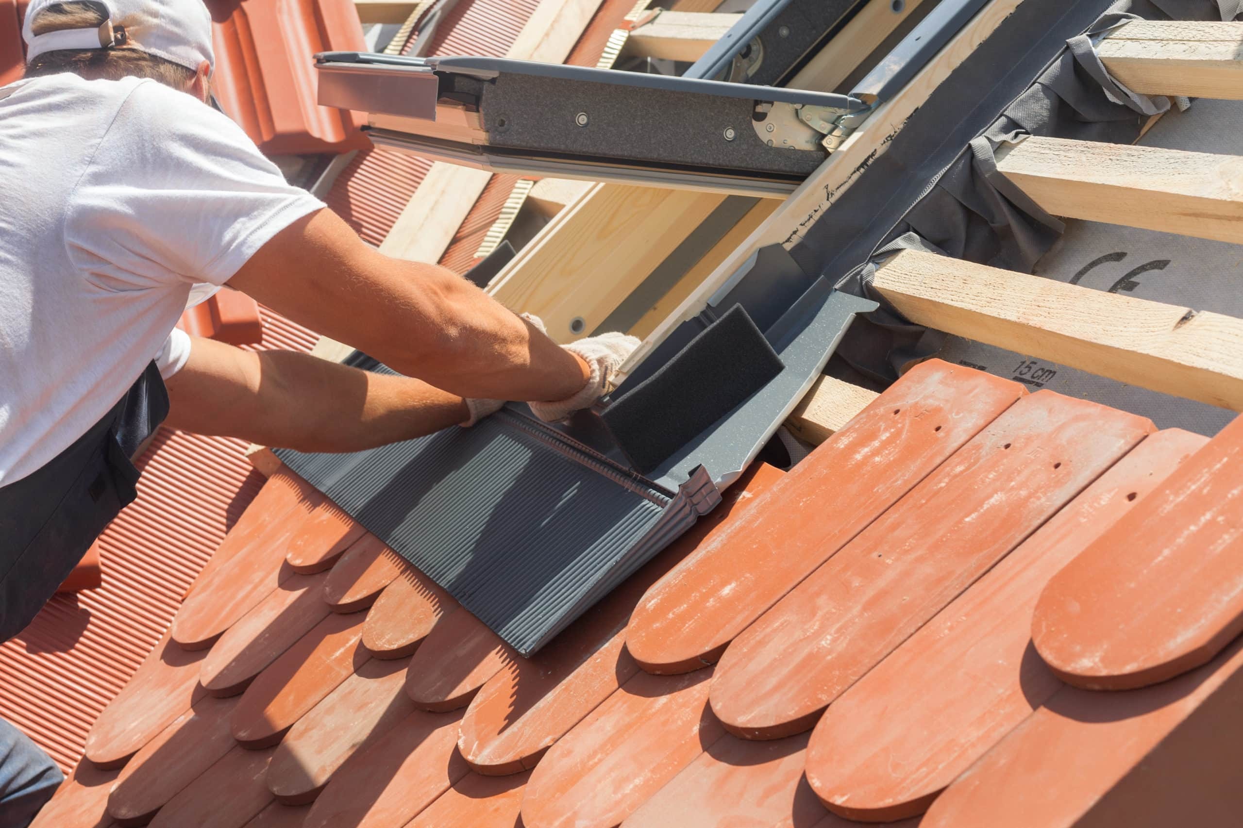 roofer attaching saddle flashing for skylight installation