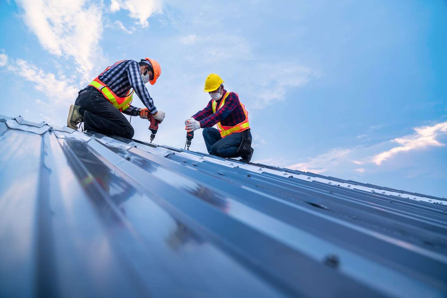 Tow construction worker safety wear using electric drill tools install on new roof metal sheet, Roof construction concept.