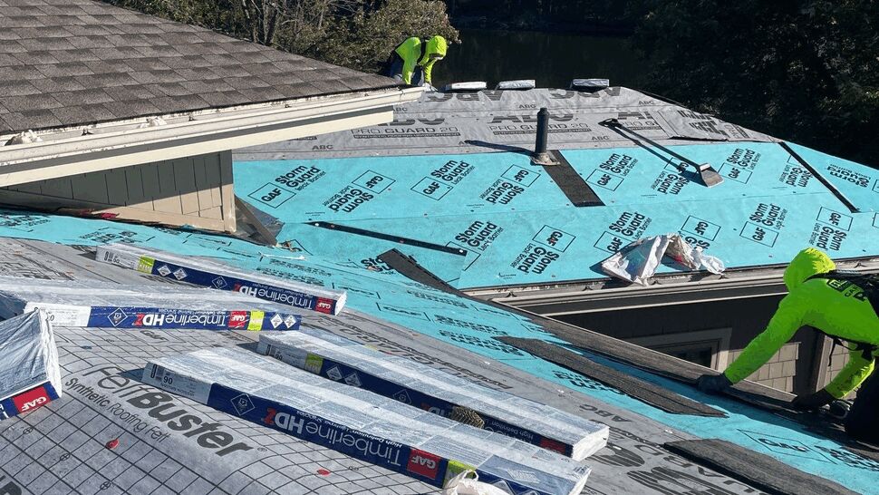 Crew installing synthetic underlayment and staging shingle bundles on a multi-level roof