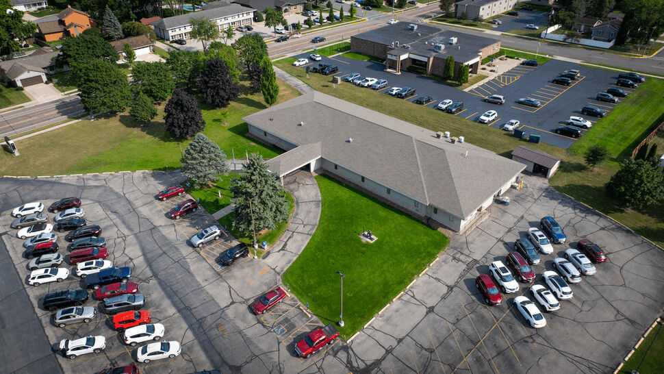 Aerial Commercial Roofing Overview | First American Roofing & Siding Inc Aerial view of a building, parking lot, and surrounding neighborhood.
