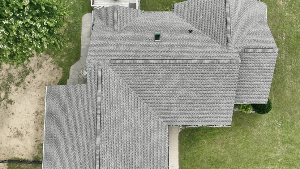 Aerial roof with skylight and ridge vents | First American Roofing & Siding Inc Top-down aerial view of a gray shingled roof with a skylight and ridge vents