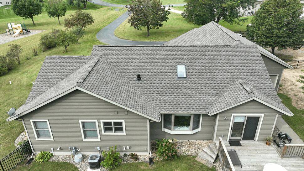 Rear elevation with vinyl siding and skylight | First American Roofing & Siding Inc Rear of house showing vinyl siding, windows, deck and shingled roof with skylight
