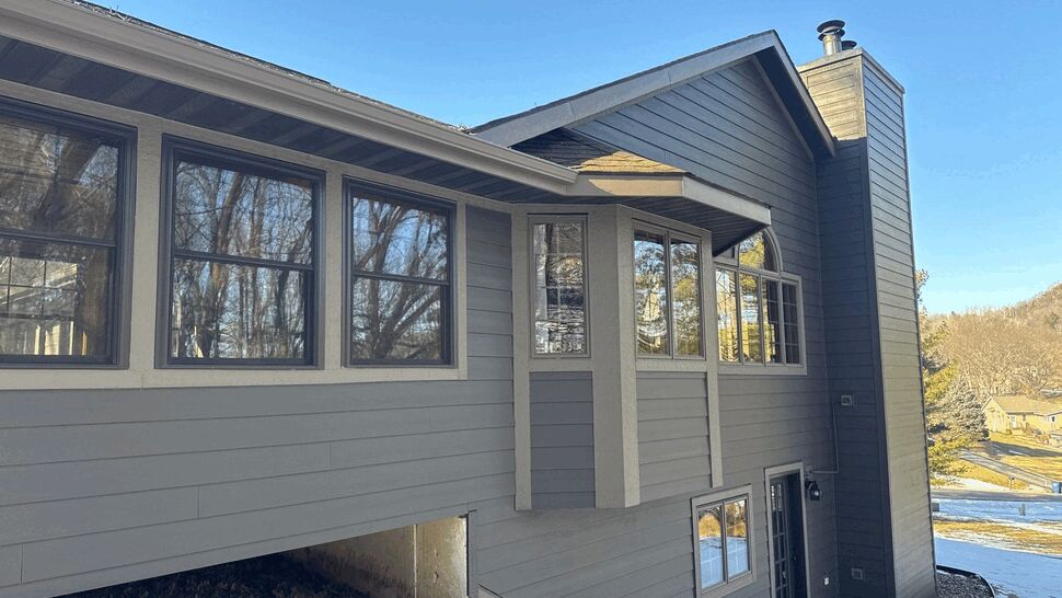 Bay window with chimney and gray siding on home exterior.