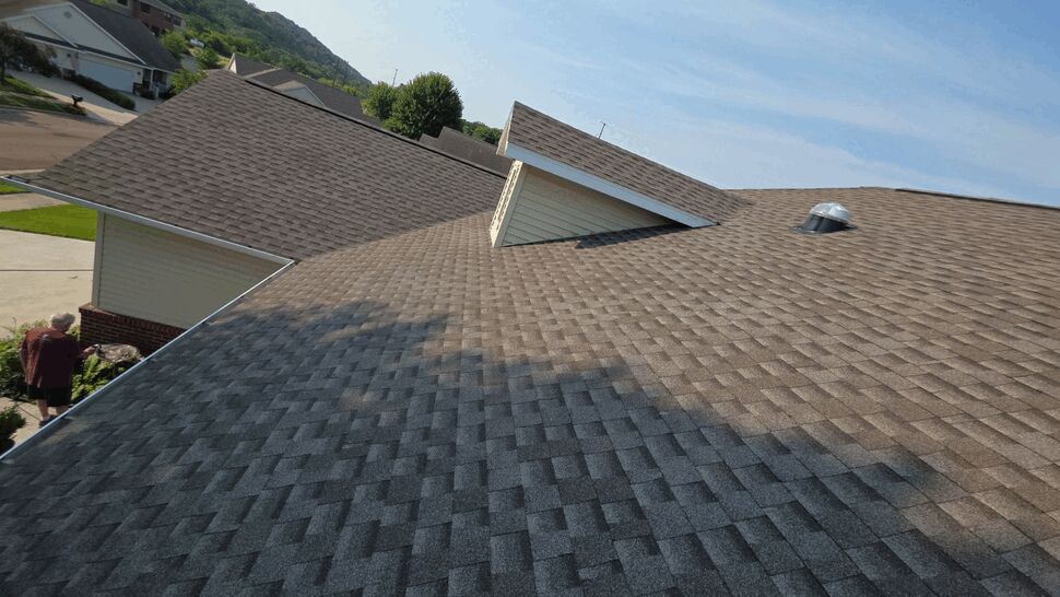 Aerial Shingle Roof Close-up | First American Roofing & Siding Inc Close-up aerial view of brown shingle roof with dormer and vent
