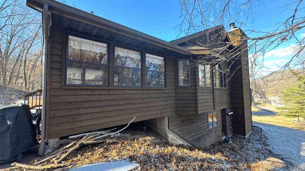 Rear elevation of home with brown wood siding and multiple windows.