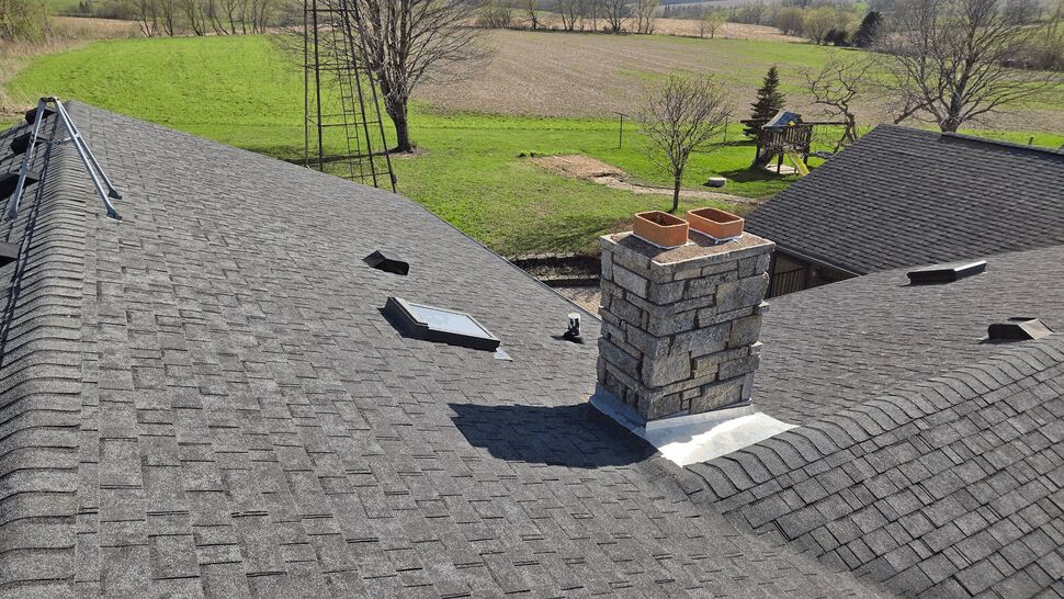 Gray shingle roof with chimney, skylight, and multiple vents