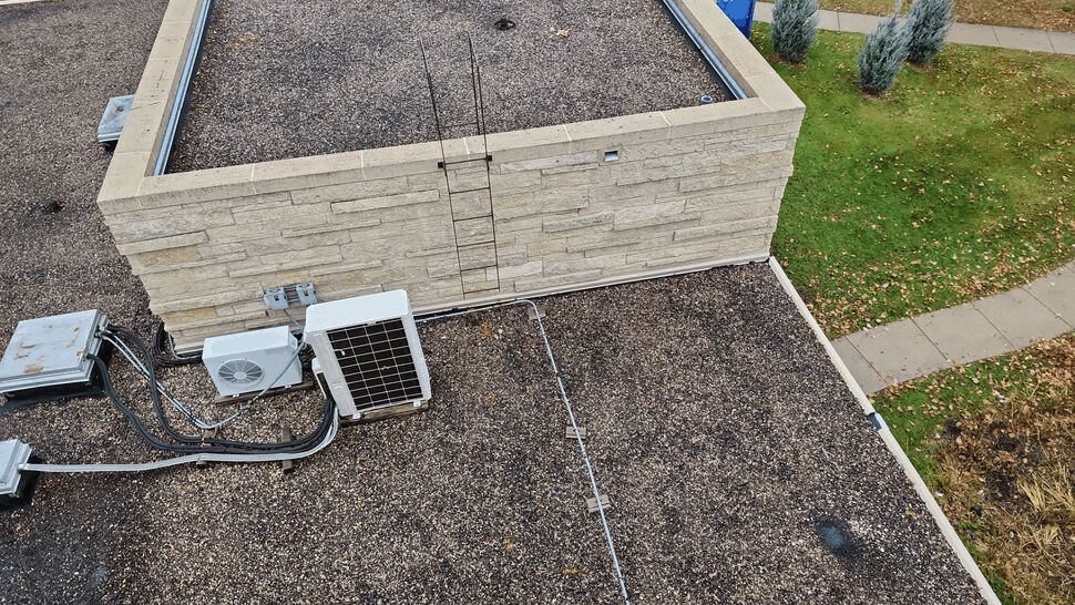 Commercial Gravel Roof Equipment | First American Roofing & Siding Inc Aerial view of a gravel-surfaced commercial roof with HVAC equipment and wall flashing