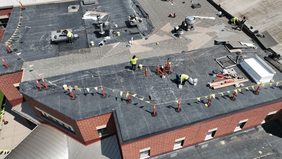 Roofing crew installing insulation and membrane materials on a flat roof
