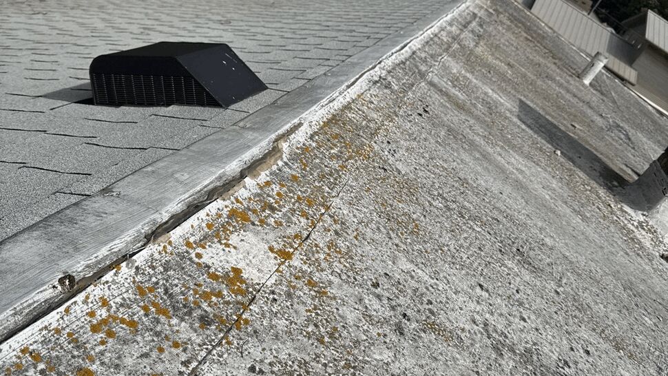 Flat commercial roof with ventilation vents beside an aged roof section.