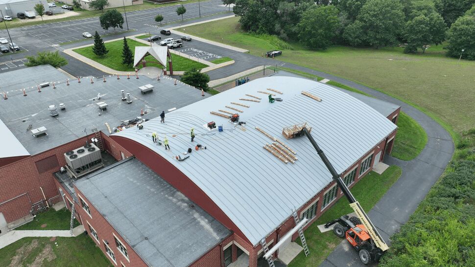 Aerial view of workers installing a light gray commercial roofing membrane