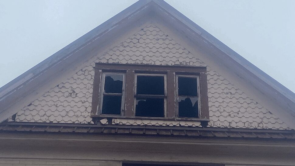 Damaged Gable Window Exterior | First American Roofing & Siding Inc Weathered gable with damaged windows and deteriorated exterior finishes