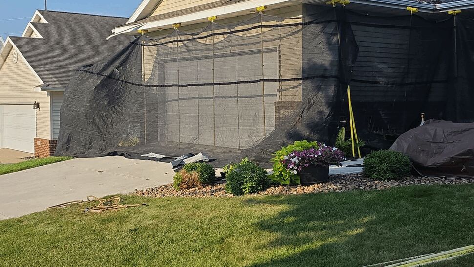 Roof Preparation with Debris Netting | First American Roofing & Siding Inc Front of house wrapped in debris netting while crew works on roof
