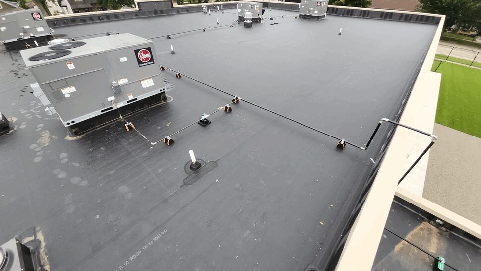 Flat black commercial roof with HVAC units and perimeter edge.