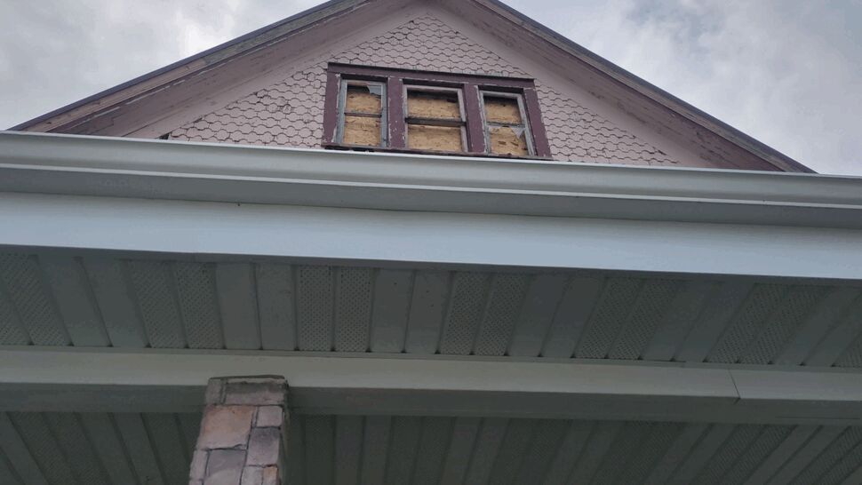 Gable Window and Gutter Damage | First American Roofing & Siding Inc Gable with damaged windows above white gutters and perforated soffits