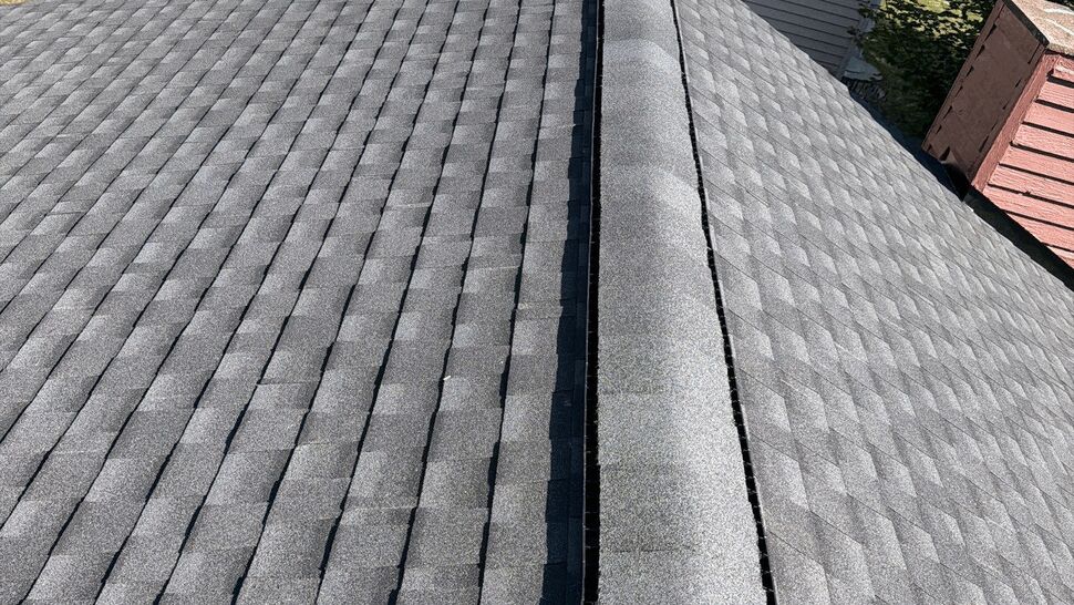 Close view of gray asphalt shingles and ridge cap on a residential roof