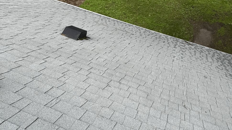 New gray asphalt shingle roof with a black exhaust vent.
