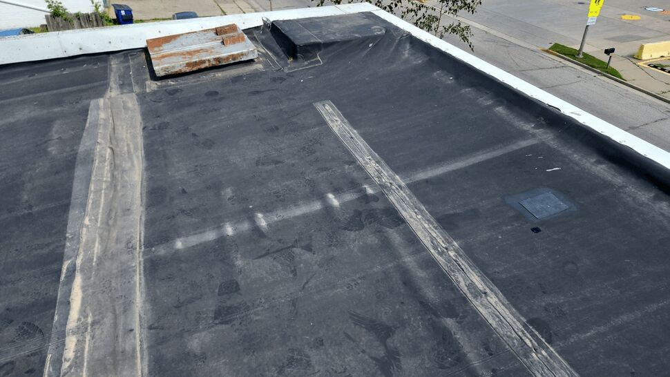 Rooftop parapet area with repaired seams and vent overlooking street
