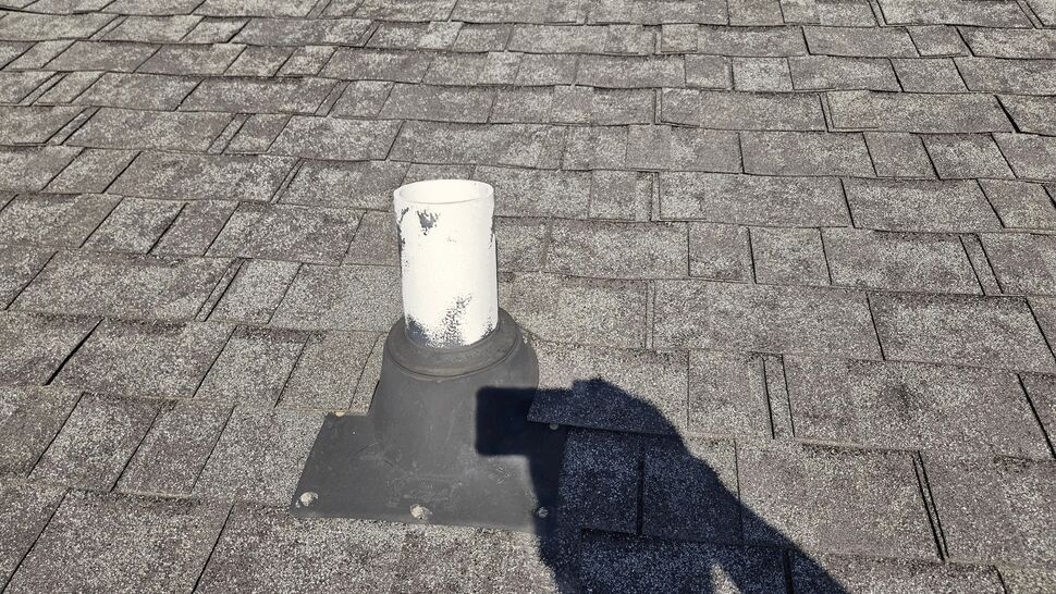 Roof pipe boot and skylight set into gray asphalt shingles