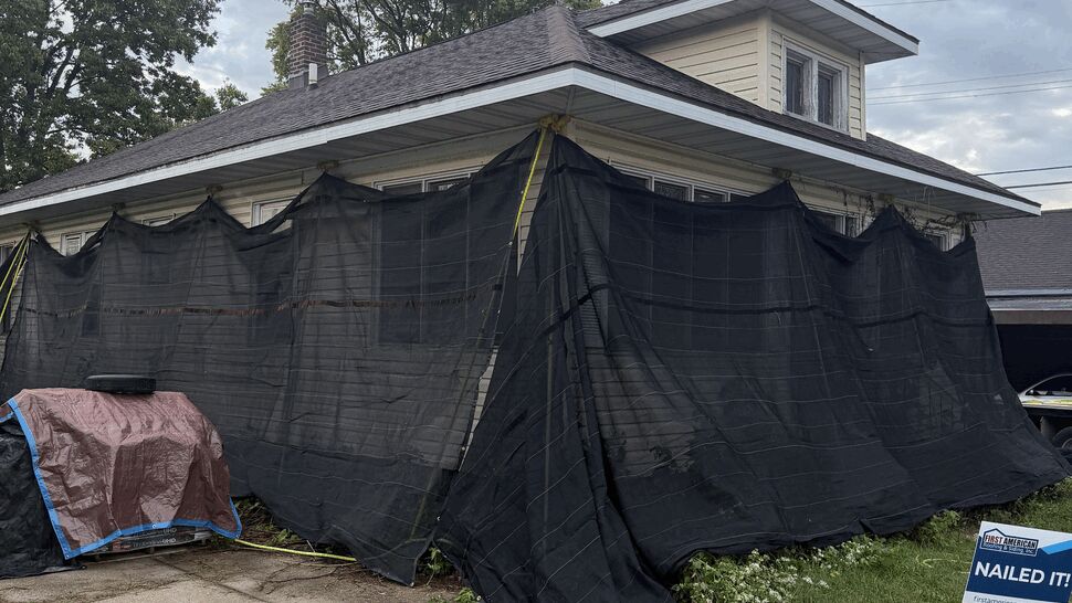 Residential roofing project protected by black exterior safety tarps