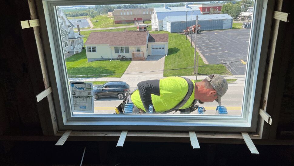 ProVia Endure Window Installation | First American Roofing & Siding Inc Installer fitting a white replacement window from inside the home