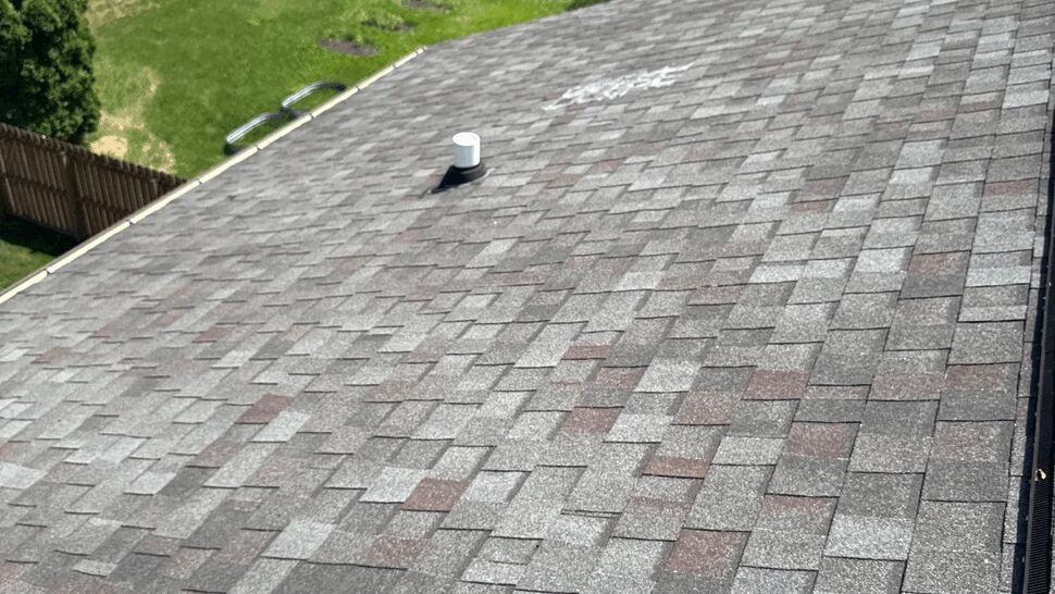 Wide view of a gray asphalt shingle roof with gutter along the edge