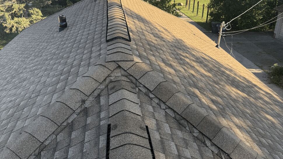 Gray shingle roof with continuous ridge vent and chimney flashing