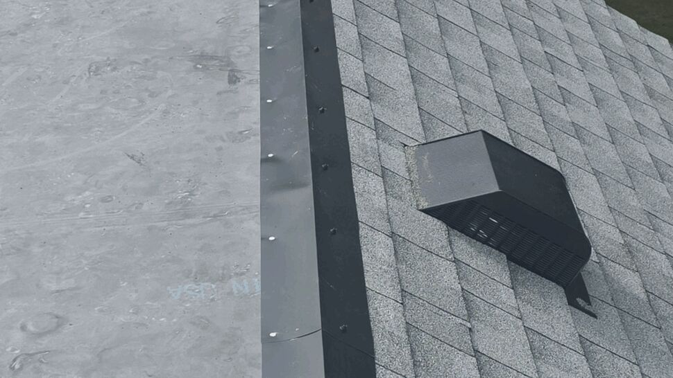 Close-up of gray asphalt shingles, ridge vent, and metal roof edging.