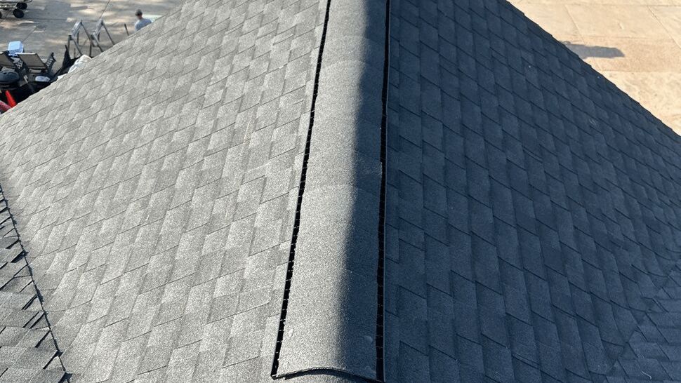 Ridge vent on shingle roof | First American Roofing & Siding Inc Top view of peaked shingle roof with newly installed ridge vent overlooking boats and a marina.