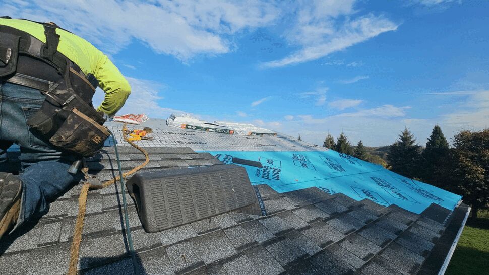 Roof installation with underlayment | First American Roofing & Siding Inc Roofer installing underlayment and shingles with tools on roof
