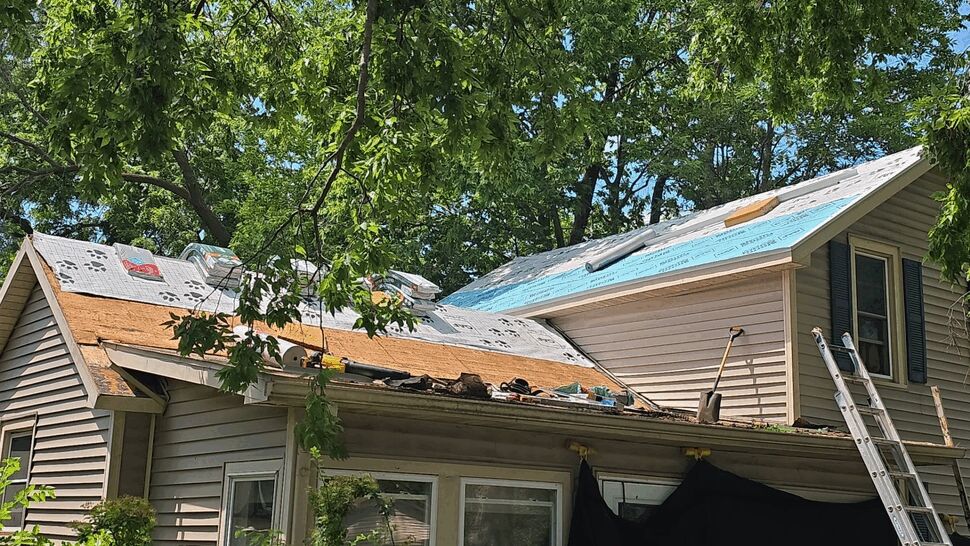 Home roof partially stripped with underlayment and ladders during replacement.