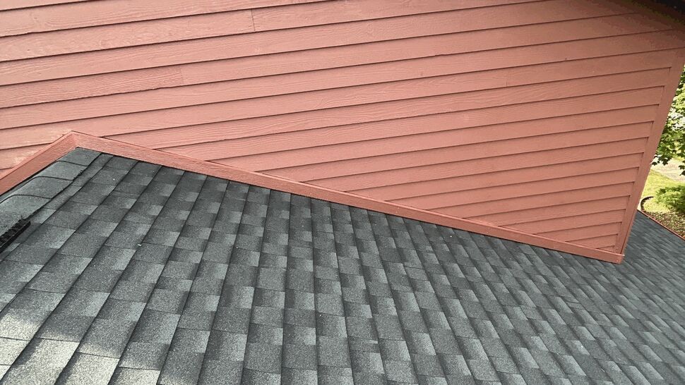 Gray shingle roof beside red horizontal siding on a residential home