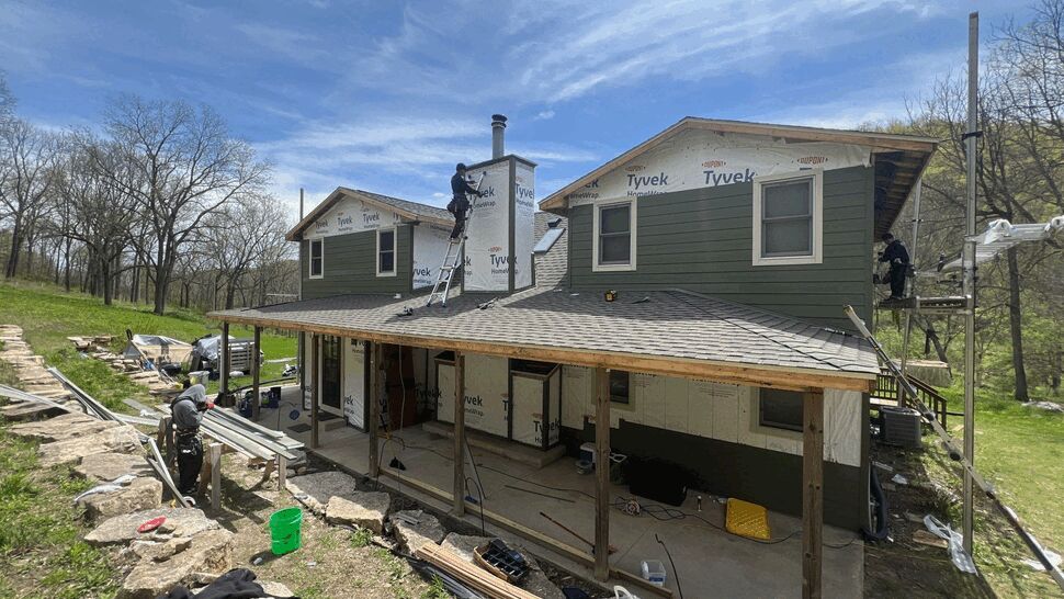 Crew installing siding and roofing underlayment on a two-story home