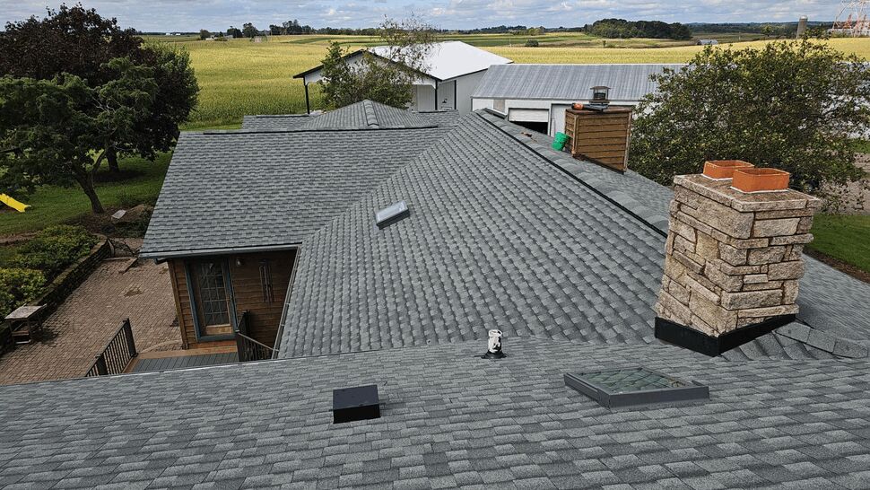 Gray asphalt shingle roof with skylight, chimney, and ventilation features