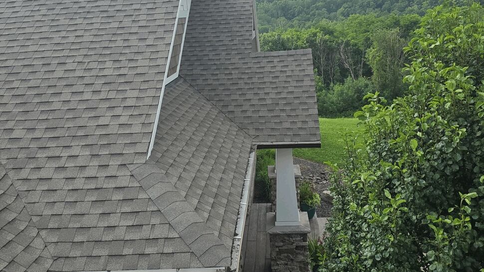 Aerial view of a gray shingled roofline with gutter and porch columns.