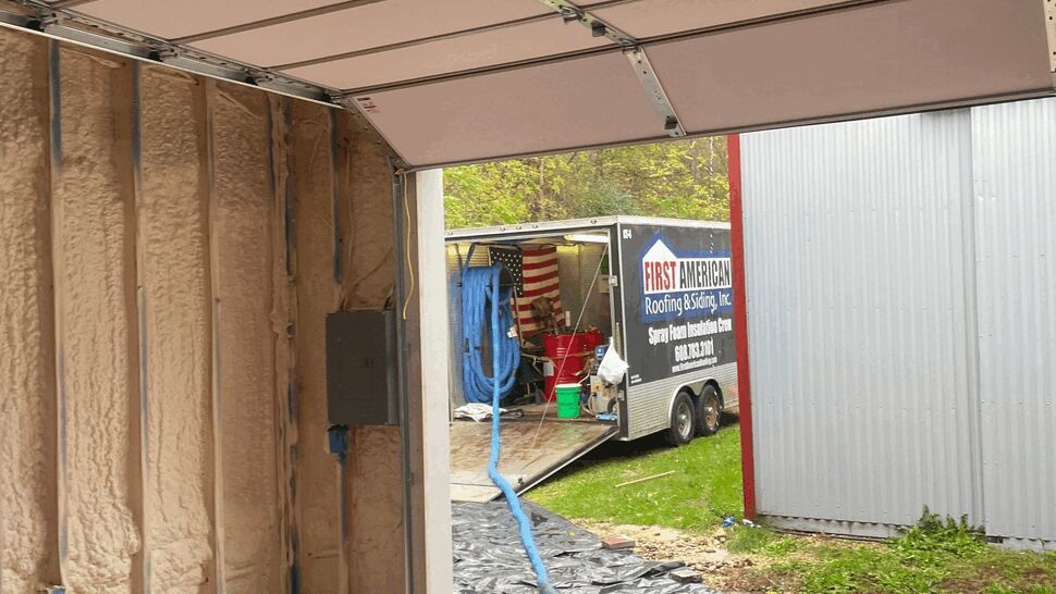 Spray Foam Equipment and Company Trailer | First American Roofing & Siding Inc Open garage door with hose leading to First American Roofing & Siding Inc trailer