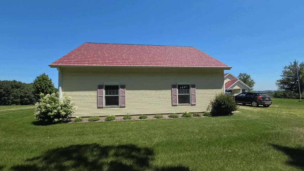 Sunny side view of house showing gutters, shutters, and parked car