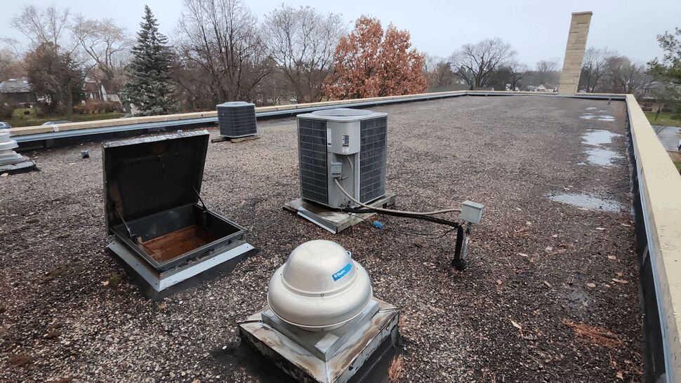 Tar and Gravel Roof Inspection | First American Roofing & Siding Inc Commercial flat roof covered with tar and gravel surfacing and rooftop HVAC equipment