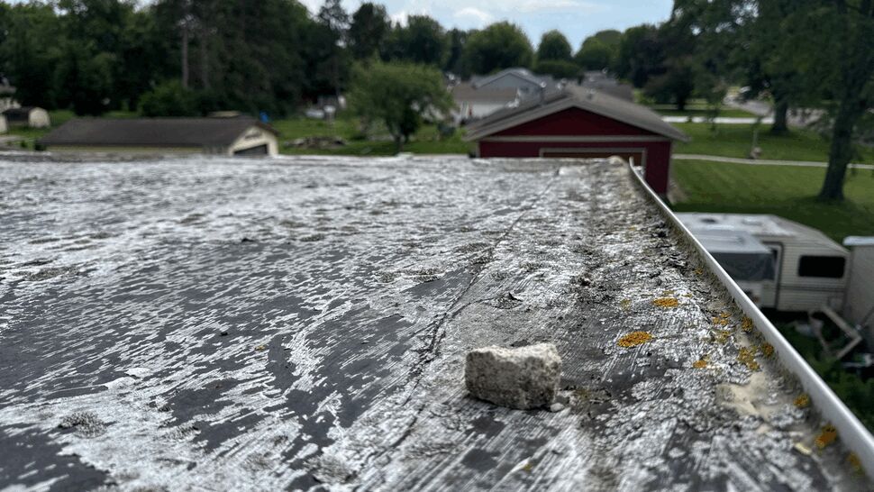 Close-up of a weathered, moss-speckled roof surface with damaged edge trim.