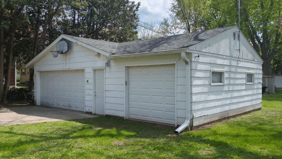 White Garage Roofing and Gutters | First American Roofing & Siding Inc White detached garage with shingle roof, garage doors, and gutters.
