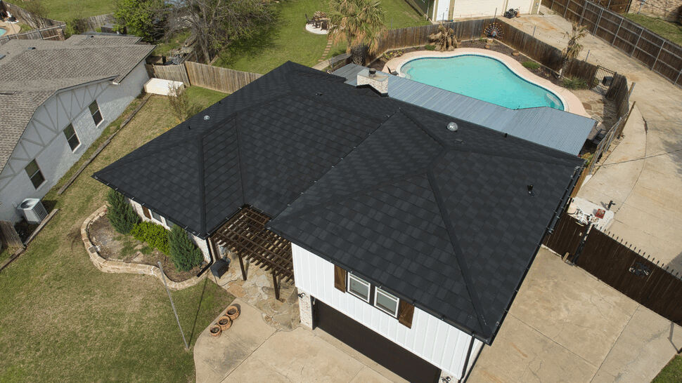 Aerial view of a house with a black roof and backyard pool
